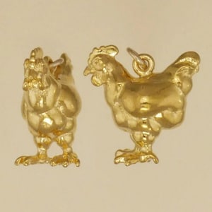 K&ouml;nnte beinhalten: Zwei goldfarbene H&uuml;hner-Anh&auml;nger. Die Anh&auml;nger sind detailliert und haben ein realistisches Aussehen.
