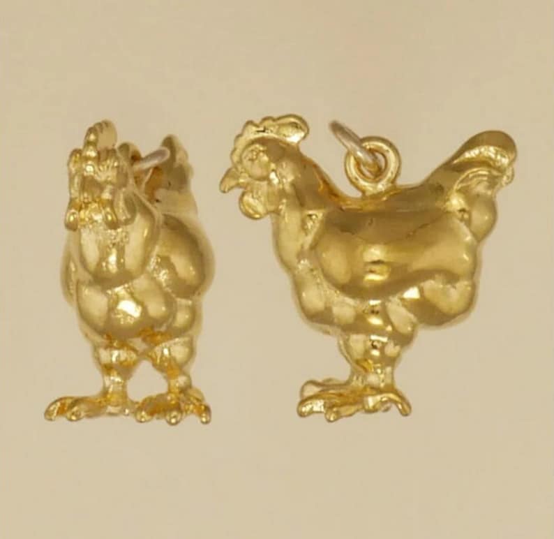 K&ouml;nnte beinhalten: Zwei goldfarbene H&uuml;hner-Anh&auml;nger. Die Anh&auml;nger sind detailliert und haben ein realistisches Aussehen.