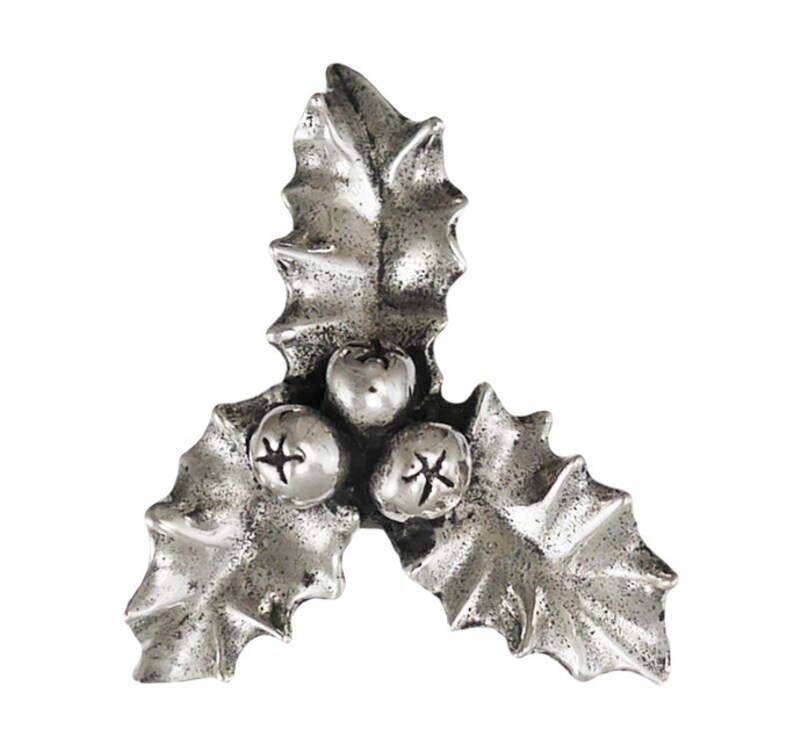 May include: A silver-coloured holly leaf and berry ornament. The ornament features three leaves and three berries. The berries have a star-like design. The leaves have a textured surface. The ornament is likely for festive decor.