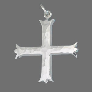 Pu&ograve; includere: Un ciondolo a forma di croce in argento con una texture martellata. La croce ha un design semplice ed elegante con una parte superiore e inferiore leggermente ornata.