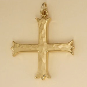 Pu&ograve; includere: Un ciondolo a forma di croce martellato color oro con un design decorativo. La croce &egrave; un simbolo religioso spesso utilizzato nei gioielli.