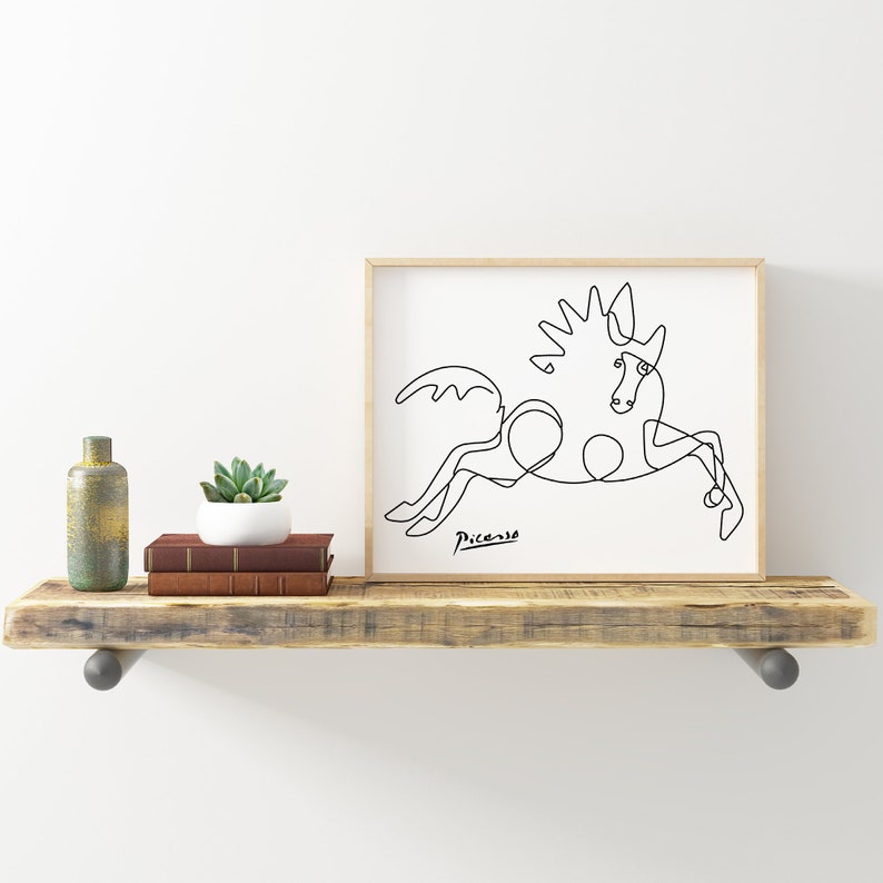 May include: A black and white line drawing of a horse, framed in a light wood frame. The drawing is signed "Picasso" in the bottom left corner.