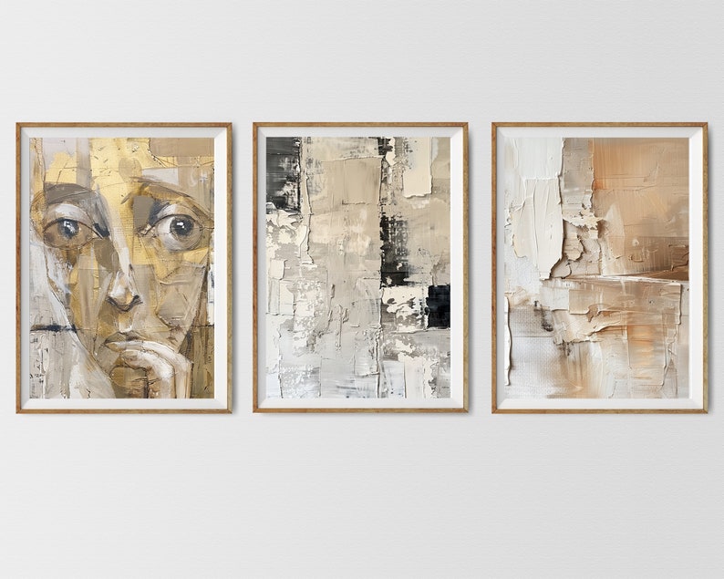 May include: Three framed abstract paintings in muted tones of brown, beige, and white. The leftmost painting features a close-up of a person's face with a contemplative expression. The middle painting is a geometric abstract design with a black rectangle in the center. The rightmost painting is a textured abstract design with a more organic feel.