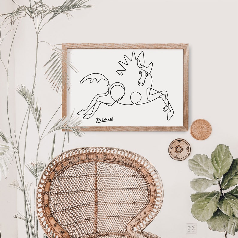 May include: A black and white line drawing of a horse, framed in a light wood frame. The drawing is signed "Picasso" in the bottom left corner.