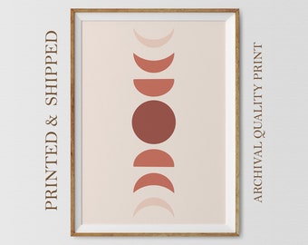 May include: A framed print with a minimalist design featuring a series of abstract circles and crescent shapes in shades of pink and brown. The print is set against a light pink background.