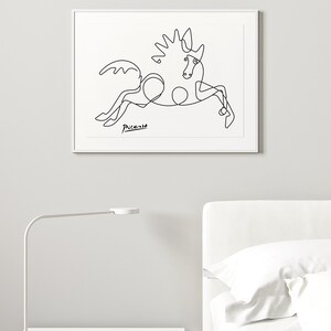 May include: A black and white line drawing of a horse, with the signature "Picasso" in the bottom left corner. The drawing is framed and hanging on a white wall.