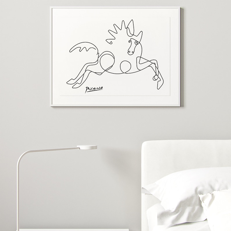 May include: A black and white line drawing of a horse, with the signature "Picasso" in the bottom left corner. The drawing is framed and hanging on a white wall.