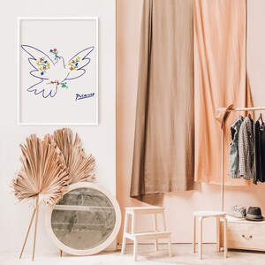 May include: A white framed print of a blue line drawing of a dove with colorful flowers. The dove is flying with its wings spread. The artist's signature "Picasso" is written in blue ink below the dove.