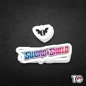 May include: A stack of white stickers with the Pokemon Sword and Shield logo in a colorful gradient. The logo is in a white circle with a black outline. The top sticker has a black and white logo of a shield with wings.