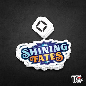 May include: A stack of white stickers with a blue, yellow and white logo that says "Shining Fates" and a black diamond symbol.