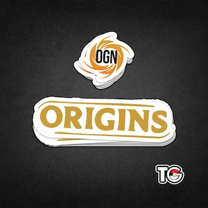 May include: White stickers with gold lettering and a black background. The word "ORIGINS" is displayed on a rectangular sticker. A smaller sticker above it has the letters "OGN" inside an orange swirl design. A third sticker with the letters "TG" is in the bottom right corner.
