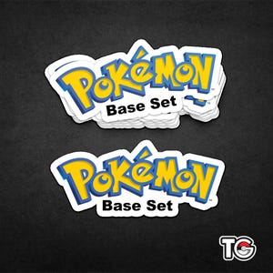 May include: A stack of white stickers featuring the "Pokémon" logo in yellow and blue with a white border. The text "Base Set" is below the logo. The stickers are on a black background.