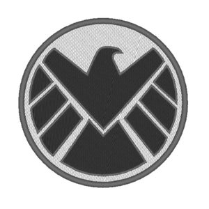 Pode incluir: Um remendo bordado em preto e branco com o logotipo da S.H.I.E.L.D. O logotipo é um círculo com uma águia cinza dentro e uma estrela cinza no centro.