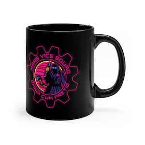 May include: Black ceramic coffee mug featuring a pink and blue graphic of a character in a hooded cloak holding a gun. The graphic is surrounded by a pink gear with the text "Mars Vice Squad Omnia Cum Pretio" in pink.