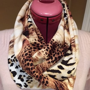May include: A brown, white and black infinity scarf with a leopard print and zebra print pattern.