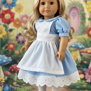 Peut inclure: Une poup&eacute;e aux longs cheveux blonds portant une robe bleu clair &agrave; manches courtes bouffantes, un tablier blanc et un col blanc. La robe pr&eacute;sente une bordure en dentelle blanche &agrave; &oelig;illets sur l'ourlet. La poup&eacute;e porte des collants blancs et des chaussures noires.
