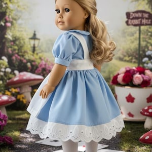Peut inclure: Une poup&eacute;e aux cheveux blonds portant une robe bleu clair avec un tablier blanc, un ourlet en dentelle blanche, des collants blancs et des chaussures noires. La poup&eacute;e est plac&eacute;e dans un jardin avec un panneau indiquant Down the Rabbit Hole.
