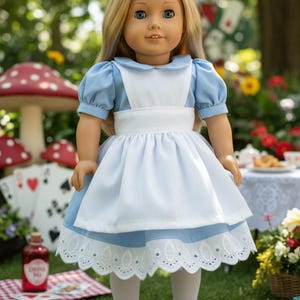 Peut inclure: Une poup&eacute;e aux longs cheveux blonds portant une robe bleu clair &agrave; manches courtes bouffantes, un tablier blanc et une bordure en dentelle blanche &agrave; l'ourlet. La poup&eacute;e a des yeux bleus, des collants blancs et des chaussures noires &agrave; boucles.