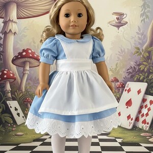 Peut inclure: Une poup&eacute;e aux cheveux blonds portant une robe bleu clair &agrave; manches courtes bouffantes, un tablier blanc avec une large ceinture, des collants blancs et des chaussures Mary Jane noires. La robe pr&eacute;sente un col rond et une bordure en dentelle.