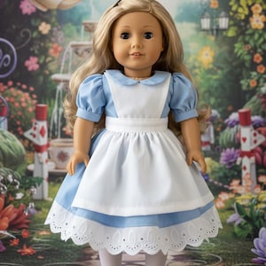 Peut inclure: Une poup&eacute;e aux longs cheveux blonds portant une robe bleu clair &agrave; manches courtes bouffantes, un col Claudine blanc et un tablier blanc. La robe pr&eacute;sente une bordure en dentelle blanche &agrave; l'ourlet, associ&eacute;e &agrave; des collants blancs et des chaussures noires.