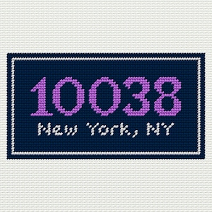 May include: A cross-stitched design featuring the zip code 10038 in lavender, set against a navy blue background. The words "New York, NY" are stitched in white below the numbers. The design is framed with a white border.
