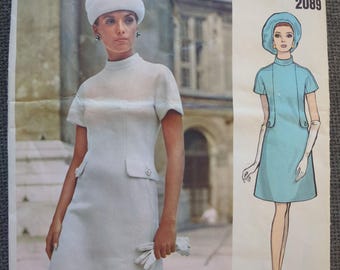 May include: Vintage Vogue Couturier Design sewing pattern featuring a woman in a white dress and hat. The pattern includes a drawing of a woman in a blue dress and matching hat. The text "Portsag of Spain" and the number "2089" are also visible.