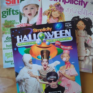 May include: Three Simplicity magazine covers featuring Halloween costume ideas. The front cover features a group of people dressed as a mummy, an Egyptian queen, a waitress, and a wrestler. The text on the cover reads "Simplicity Halloween Celebrate the Century Over 400 Costumes".