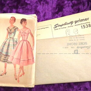 May include: Vintage Simplicity sewing pattern packet, featuring illustrations of two women in dresses. The packet includes a "Simplicity primer" guide and a "Skirt Front" pattern piece. The pattern is size 14 and priced at 35 cents.