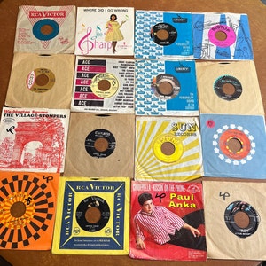 May include: A collection of 12 vintage 45 rpm record sleeves. The sleeves are in various colours and feature different artists and song titles. Some of the sleeves have a yellow background with black text, while others have a blue background with white text. The sleeves are all in good condition and would be a great addition to any record collection.