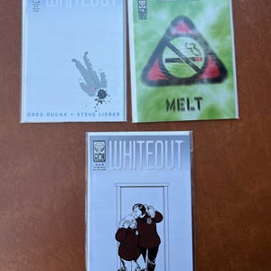 May include: Three comic book covers for Whiteout, a graphic novel series. The covers are white with black text and illustrations. The first cover shows a person falling from the sky. The second cover shows a no smoking sign with the word "Melt" below it. The third cover shows two people standing in a doorway.