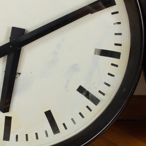 K&ouml;nnte beinhalten: Ein schwarz-wei&szlig;es Zifferblatt mit schwarzen Zeigern. Die Uhr befindet sich in einem schwarzen runden Geh&auml;use.