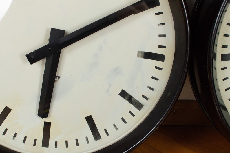 K&ouml;nnte beinhalten: Ein schwarz-wei&szlig;es Zifferblatt mit schwarzen Zeigern. Die Uhr befindet sich in einem schwarzen runden Geh&auml;use.