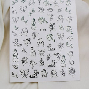 May include: A sheet of white nail stickers with black line drawings of faces, butterflies, flowers, and other abstract designs. The sheet has the number 1119 printed on it.