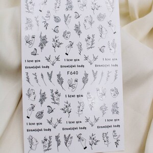 May include: A sheet of black and white nail art stickers with various designs, including faces, flowers, butterflies, and the text "I love you Beautiful lady F640".