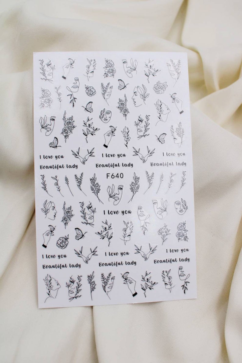 May include: A sheet of black and white nail art stickers with various designs, including faces, flowers, butterflies, and the text "I love you Beautiful lady F640".