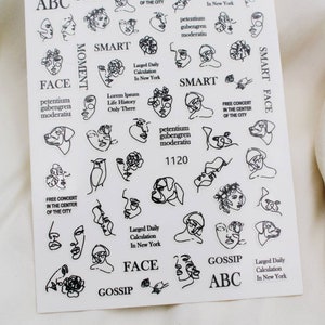 May include: A sheet of black and white nail stickers with various designs, including faces, flowers, and text. The text includes "ABC Face", "Smart", "Gossip", "Free Concert in the Center of the City", "Larged Daily Calculation in New York", "Petentium Gubengren Moderatiu", "Lorem Ipsum Life History Only There", and "1120".