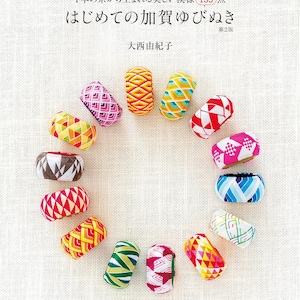 以下が含まれることがあります： 「加賀指ぬきの始め方」というタイトルの日本語の本の表紙。白い背景に、それぞれがユニークな幾何学模様を持つ、カラフルな加賀指ぬきが円形に並んでいます。