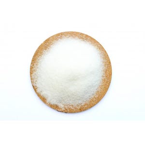 May include: A circular, light brown object with a white, granular substance piled on top. The object is set against a plain white background. The granular substance appears to be sugar or a similar food product.