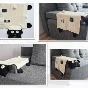 May include: A cream-colored, knitted sofa armrest organizer shaped like a sheep. It features a sheep head, two pockets, and black hooves. The organizer is designed to hold remote controls and other small items.