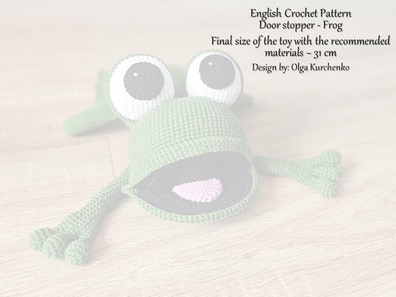 May include: Green crocheted frog doorstop with large white eyes and a pink tongue. The frog is 31 cm in size.