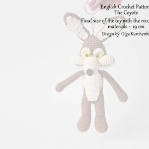 May include: A handmade crochet coyote toy, featuring brown and cream colors, with yellow eyes and a black nose. The toy is approximately 19 cm in size. The image includes text: "English Crochet Pattern The Coyote".