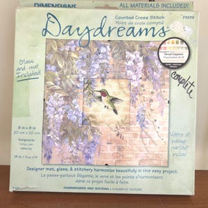 Puede incluir: Kit de punto de cruz "Daydreams" con un diseño de colibrí y glicinia. El kit incluye una esterilla de diseño, cristal y costura. La pieza terminada mide 20 cm por 20 cm.