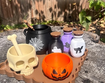 May include: A digital download set featuring a black cauldron with a white spiderweb, a beige skull mortar and pestle, an orange pumpkin bowl, and three small potion bottles in black, purple, and white with ghost, witch, and cat graphics.