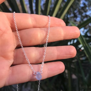 Puede incluir: Un collar de cadena de plata con un solo colgante de cuentas de vidrio esmerilado.