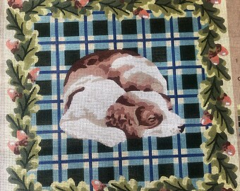 Tapiz estampado con la imagen de un perro durmiendo sobre una alfombra de tartán.