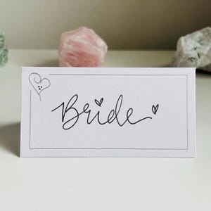 Elegantes tarjetas de lugar para bodas escritas a mano: modernas tarjetas de nombre para mesas en blanco y plateado para eventos
