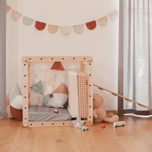 May include: A wooden playhouse with a slide, a teddy bear, and a variety of toys. The playhouse is decorated with a colorful fabric garland.