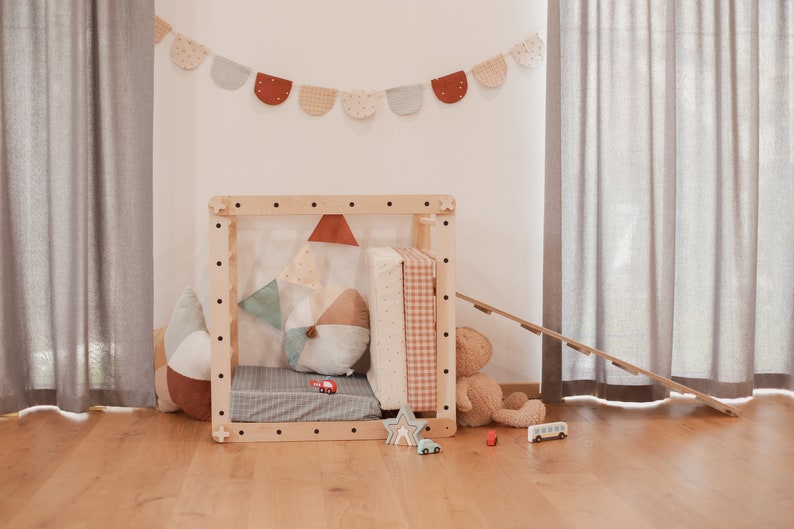 May include: A wooden playhouse with a slide, a teddy bear, and a variety of toys. The playhouse is decorated with a colorful fabric garland.