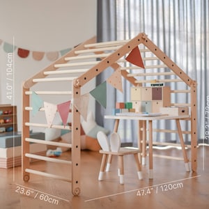 May include: A wooden climbing frame with a house-like structure, measuring 41 inches (104 cm) high, 23.6 inches (60 cm) wide, and 47.4 inches (120 cm) long. It includes a small table, a chair with bunny ears, and colorful bunting. The table is 28.3 inches (72 cm) high.