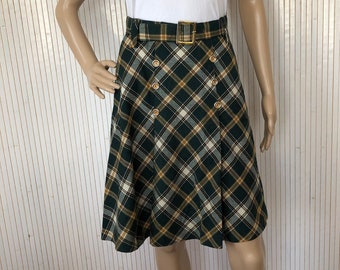 May include: A green and yellow plaid skirt with a gold buckle belt and gold buttons. The skirt is knee-length and has a flared silhouette.